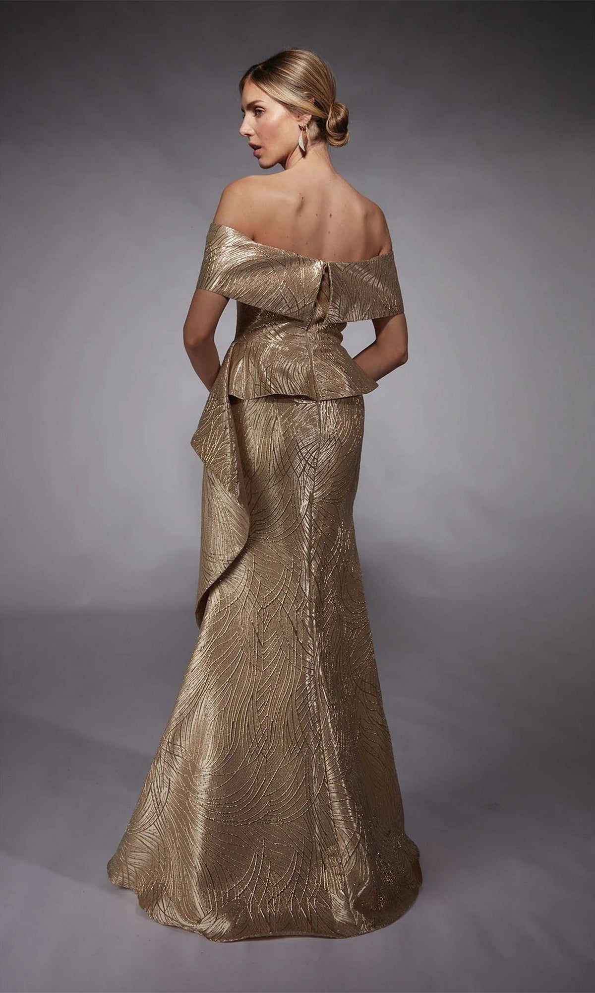 A woman models the Alyce 27759 long formal dress—a gold, off-the-shoulder jacquard gown with textured patterns and a fitted bodice—against a plain studio backdrop.